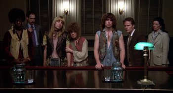 Movie still from “Hair” (1979), directed by Milos Forman – A group of people standing in front of a counter; Medium shot, Low angle