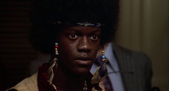 Movie still from “Hair” (1979), directed by Milos Forman – A man with a large afro wearing a headdress; Close Up shot, Low angle