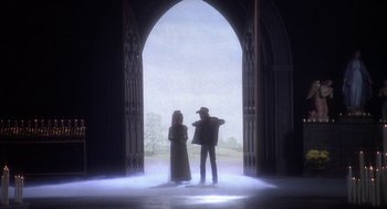 Movie still from “Hair” (1979), directed by Milos Forman – A man and a woman standing in front of an arched doorway; Wide shot, Low angle