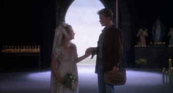 Movie still from “Hair” (1979), directed by Milos Forman – A man and a woman holding hands in front of an archway; Medium shot, Over the shoulder angle