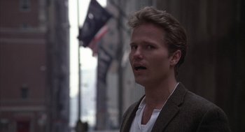 Movie still from “Hair” (1979), directed by Milos Forman – A man in a brown jacket standing in front of a building; Close Up shot, Over the shoulder angle