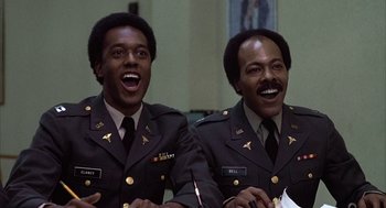 Movie still from “Hair” (1979), directed by Milos Forman – A couple of men in military uniforms smiling for a picture; Close Up shot, Low angle