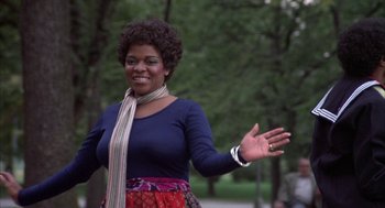 Movie still from “Hair” (1979), directed by Milos Forman – A woman in a blue shirt and a red and purple skirt; Medium shot, Low angle