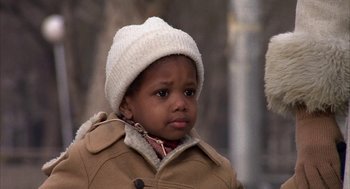 Movie still from “Hair” (1979), directed by Milos Forman – A little boy wearing a coat and a white hat; Close Up shot, Over the shoulder angle