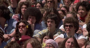 Movie still from “Hair” (1979), directed by Milos Forman – A group of people sitting in a crowd watching a performance; Close Up shot, High angle