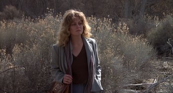 Movie still from “Hair” (1979), directed by Milos Forman – A woman standing in a wooded area holding a purse; Medium shot, Low angle