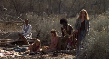 Movie still from “Hair” (1979), directed by Milos Forman – A group of people sitting on the ground in a field; Wide shot, Low angle