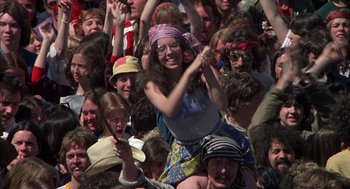 Movie still from “Hair” (1979), directed by Milos Forman – A crowd of people sitting and standing in a field; Medium shot, High angle