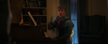 Movie still from “Halloween Ends” (2022), directed by David Gordon Green – A man holding a bottle of beer near a piano; Medium shot, Low angle