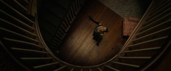 Movie still from “Halloween Ends” (2022), directed by David Gordon Green – A woman sitting on the floor of a wooden staircase; Wide shot, Overhead angle