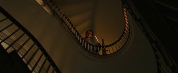 Movie still from “Halloween Ends” (2022), directed by David Gordon Green – A man is standing on a spiral stair case; Wide shot, Low angle