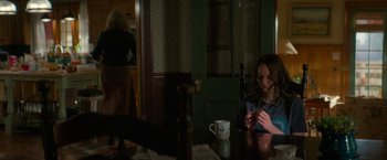 Movie still from “Halloween Ends” (2022), directed by David Gordon Green – A woman sitting at a table with a wine glass; Medium shot, Over the shoulder angle