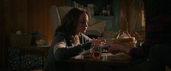 Movie still from “Halloween Ends” (2022), directed by David Gordon Green – A woman sitting at a table with a glass of wine in front of her; Medium shot, Over the shoulder angle