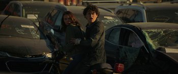 Movie still from “Halloween Ends” (2022), directed by David Gordon Green – A man and a woman on a motorcycle in a parking lot; Medium shot, Low angle
