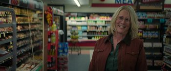 Movie still from “Halloween Ends” (2022), directed by David Gordon Green – A woman standing in front of an aisle in a grocery store; Medium shot, Over the shoulder angle