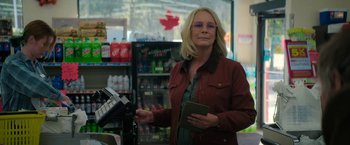 Movie still from “Halloween Ends” (2022), directed by David Gordon Green – A woman standing in front of a cash register in a store; Medium shot, Over the shoulder angle