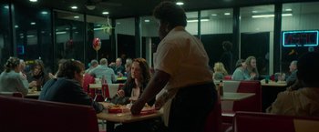 Movie still from “Halloween Ends” (2022), directed by David Gordon Green – A woman standing at a table in front of a man; Medium shot, Over the shoulder angle