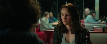 Movie still from “Halloween Ends” (2022), directed by David Gordon Green – A woman sitting in front of a group of people in a room; Medium shot, Over the shoulder angle