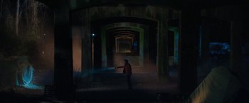 Movie still from “Halloween Ends” (2022), directed by David Gordon Green – A man standing in a dark room holding a gun; Extreme Wide shot, High angle