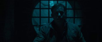 Movie still from “Halloween Ends” (2022), directed by David Gordon Green – A man standing in front of a window in a dark room; Medium shot, High angle