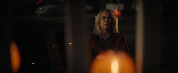 Movie still from “Halloween Ends” (2022), directed by David Gordon Green – A woman in a brown jacket looking out of a window; Medium shot, Over the shoulder angle