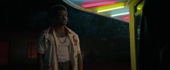 Movie still from “Halloween Ends” (2022), directed by David Gordon Green – A man standing in front of a neon sign at night; Medium shot, Low angle