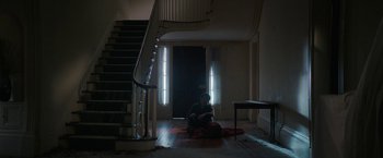 Movie still from “Halloween Ends” (2022), directed by David Gordon Green – A woman sitting on the floor in front of a staircase; Wide shot, High angle