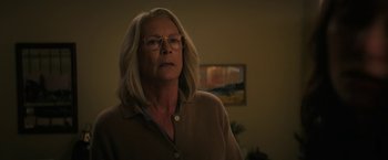 Movie still from “Halloween Ends” (2022), directed by David Gordon Green – A woman with blonde hair wearing glasses in a room; Medium shot, Over the shoulder angle
