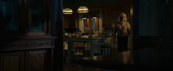 Movie still from “Halloween Ends” (2022), directed by David Gordon Green – A woman standing in front of a kitchen counter; Wide shot, Over the shoulder angle