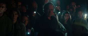 Movie still from “Halloween Ends” (2022), directed by David Gordon Green – A group of people standing in a dark room with lights on; Medium shot, Over the shoulder angle