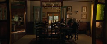Movie still from “Halloween Ends” (2022), directed by David Gordon Green – Two people are sitting at a dining room table; Wide shot, High angle