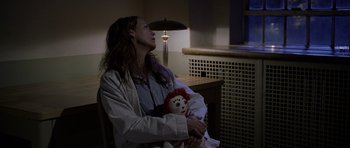 Movie still from “Halloween: Resurrection” (2002), directed by Rick Rosenthal – A person holding a doll in a room; Medium shot, Over the shoulder angle