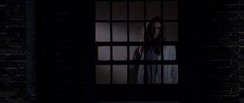 Movie still from “Halloween: Resurrection” (2002), directed by Rick Rosenthal – A woman standing in front of a window with bars; Medium shot, Low angle