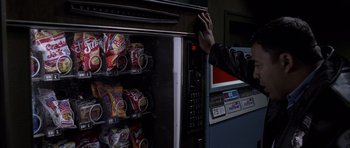 Movie still from “Halloween: Resurrection” (2002), directed by Rick Rosenthal – A person reaching for a bag of chips in a vending machine; Medium shot, High angle