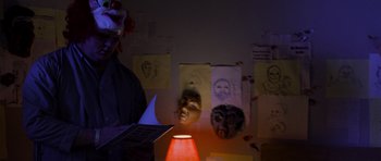 Movie still from “Halloween: Resurrection” (2002), directed by Rick Rosenthal – A clown and a lamp in a room; Medium shot, Over the shoulder angle