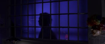 Movie still from “Halloween: Resurrection” (2002), directed by Rick Rosenthal – A shadow of a person behind bars in a dark room; Medium shot, Low angle