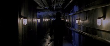 Movie still from “Halloween: Resurrection” (2002), directed by Rick Rosenthal – A man walking down a dark hallway at night; Wide shot, High angle