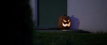 Movie still from “Halloween: Resurrection” (2002), directed by Rick Rosenthal – A lit pumpkin sitting in front of a door; Extreme Close Up shot, Low angle