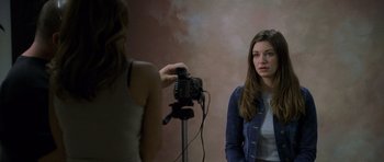 Movie still from “Halloween: Resurrection” (2002), directed by Rick Rosenthal – A woman is taking a picture of another woman in front of a camera; Medium shot, Over the shoulder angle