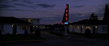 Movie still from “Halloween: Resurrection” (2002), directed by Rick Rosenthal – A motel sign lit up at night in the dark; Extreme Wide shot, High angle