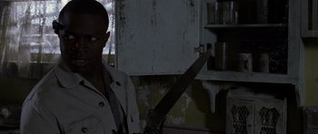 Movie still from “Halloween: Resurrection” (2002), directed by Rick Rosenthal – A man holding a large saw in a room; Close Up shot, Over the shoulder angle