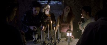 Movie still from “Halloween: Resurrection” (2002), directed by Rick Rosenthal – A group of people standing around a table with lit candles; Medium shot, Low angle