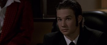 Movie still from “Halloween: Resurrection” (2002), directed by Rick Rosenthal – A man in a suit and tie sitting in a chair; Close Up shot, High angle
