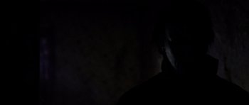 Movie still from “Halloween: Resurrection” (2002), directed by Rick Rosenthal – A person is standing in the dark with their head turned to the side; Close Up shot, Low angle