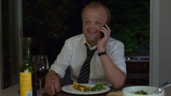 Movie still from “Happy End” (2017), directed by Michael Haneke – A man sitting at a dinner table talking on a cell phone; Close Up shot, Over the shoulder angle