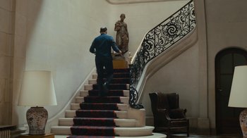 Movie still from “Happy End” (2017), directed by Michael Haneke – A man walking up the stairs of a hotel room; Wide shot, Low angle