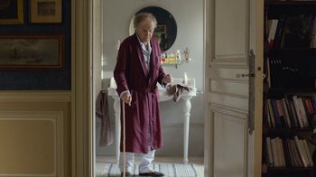 Movie still from “Happy End” (2017), directed by Michael Haneke – An old man in a robe is standing in a bathroom; Wide shot, Low angle