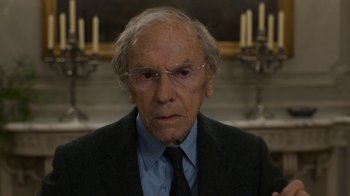 Movie still from “Happy End” (2017), directed by Michael Haneke – An old man wearing glasses and a suit; Close Up shot, Over the shoulder angle