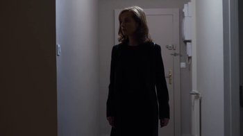 Movie still from “Happy End” (2017), directed by Michael Haneke – A woman standing in front of a door in a room; Medium shot, Low angle