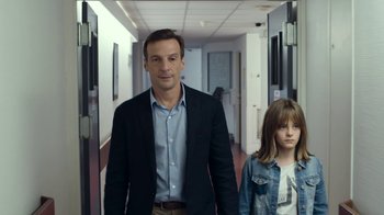 Movie still from “Happy End” (2017), directed by Michael Haneke – A man and a girl walking down a hall way; Medium shot, Low angle